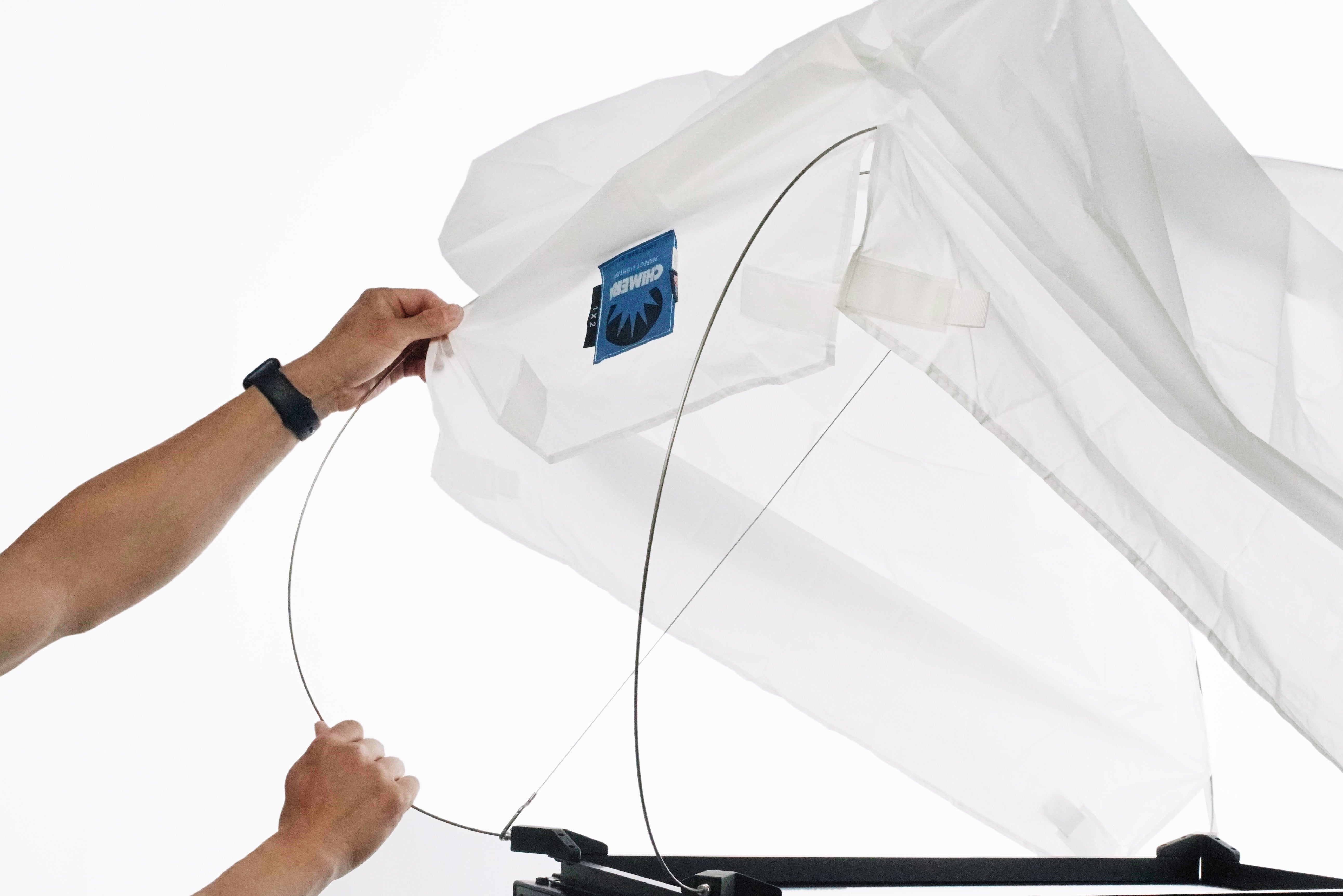 Person adjusting a Chimera lantern for 1x2 LED panels in photography setup.